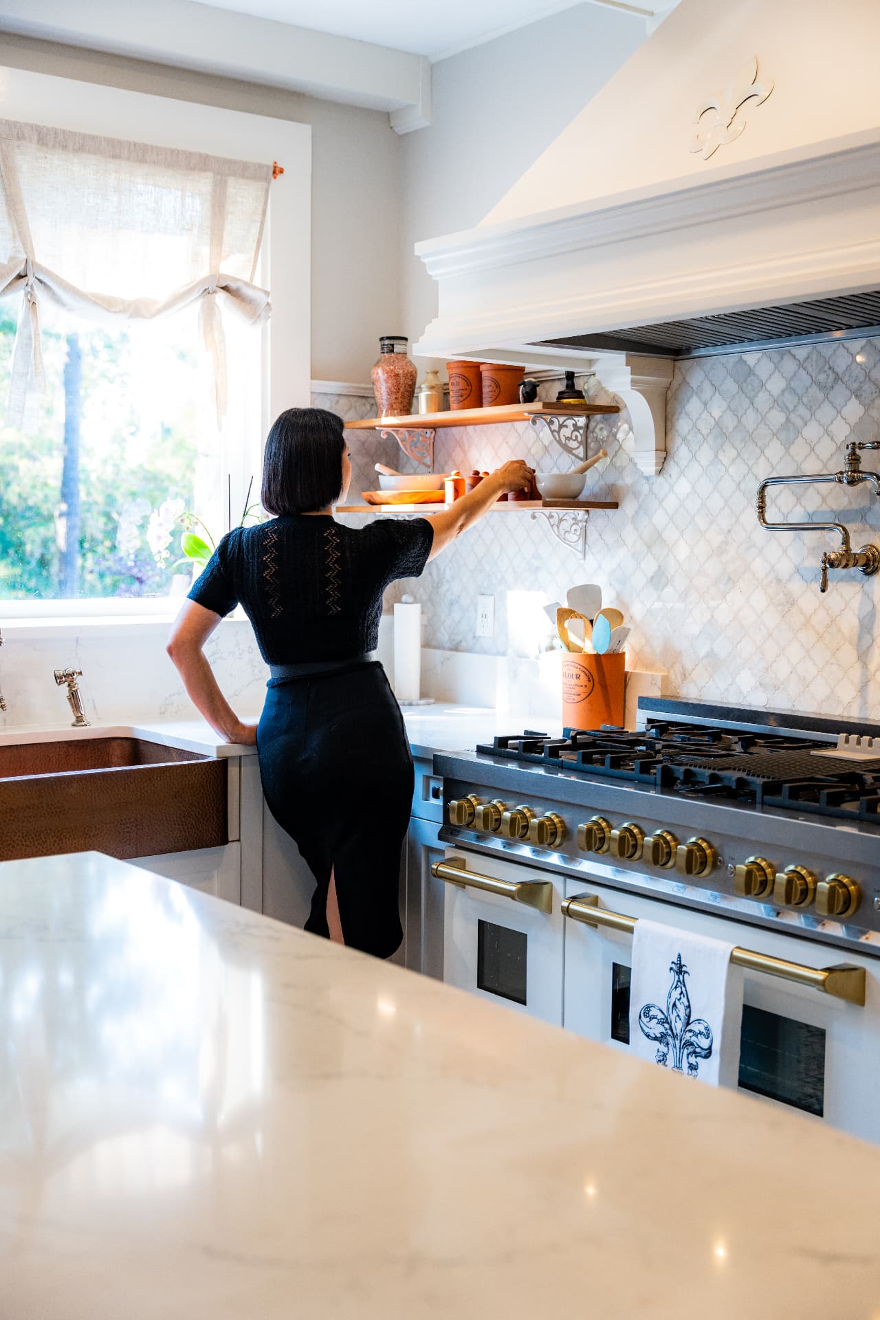 High-end kitchen interior with a woman in black standing by a premium range stove